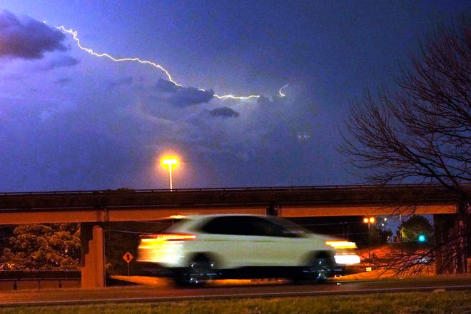 A vehicle races along a Jackson, Miss., street as lightning streaks across the sky, Tuesday evening, Nov. 29, 2022. Area residents were provided a light show as severe weather accompanied by some potential twisters affected parts of Louisiana and Mississippi.