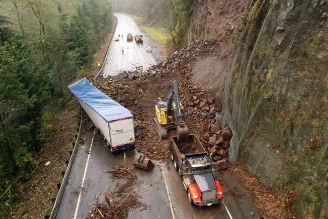 In this photo provided by the Oregon Department of Transportation, crews work to clear debris and remove a disabled truck on U.S. 30 east of Astoria, Ore., Wednesday, Nov. 30, 2022, after a landslide Tuesday night. (Oregon Department of Transportation via AP)