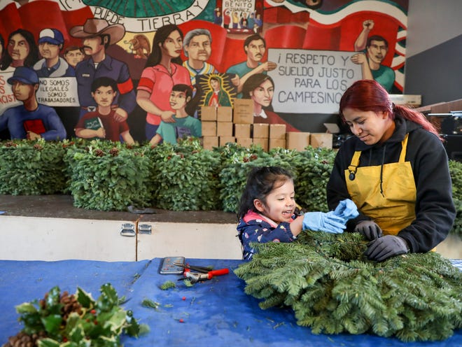 Zulema Gaspar, 4, and Jessica Dirzio Ramirez, 18, make Christmas wreaths for Mujeres Luchadores Progresistas' annual drive in Salem.