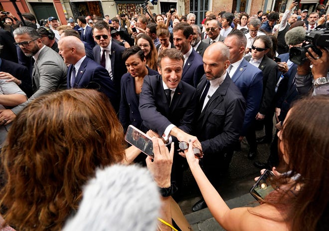 French President Emmanuel Macron greets the crowd as he walks down Royal Street in the French Quarter of New Orleans during a Dec. 2 visit. Next to him is New Orleans Mayor Latoya Cantrell.