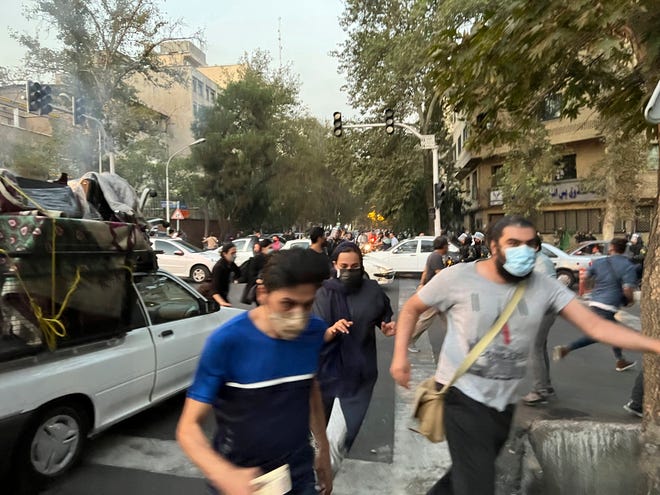 In this Monday, Sept. 19, 2022, photo taken by an individual not employed by the Associated Press and obtained by the AP outside Iran, people run away from anti-riot police during a protest over the death of a young woman who had been detained for violating the country's conservative dress code, in downtown Tehran, Iran.