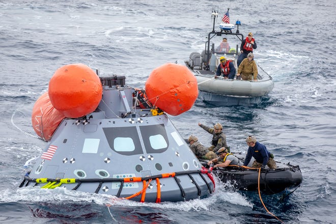 Navy divers attach maintenance tethers to a mock Orion capsule during the weeklong En route 9 Rescue Test from the USS John P. Murtha in the Pacific Ocean in November 2021.