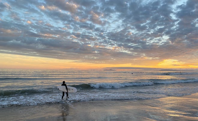 A sunset lights up a cloudy sky during a break in the weekend rain at Surfers Point in Ventura Saturday.