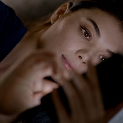 A woman looks at her phone while in bed.