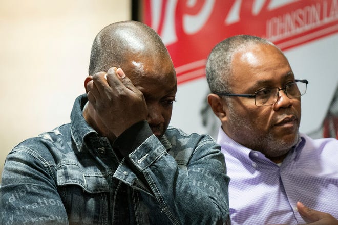 Peter Lyoya, the father of Patrick Lyoya, left, becomes emotional while watching video footage, flanked by family pastor and interpreter Israel Siku, during a press conference to announce the filing of a civil lawsuit on behalf of Patrick Lyoya's family against the City of Grand Rapids and former Grand Rapids police officer Christopher Schurr at The Westin in Detroit on Wednesday, December 7, 2022.