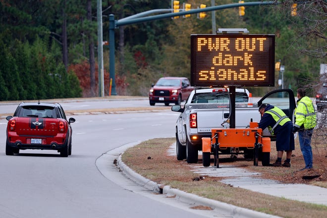Workers set up a display, warning drivers on NC211 of the power outage in the area and how to approach the upcoming intersections in Southern Pines, North Carolina
