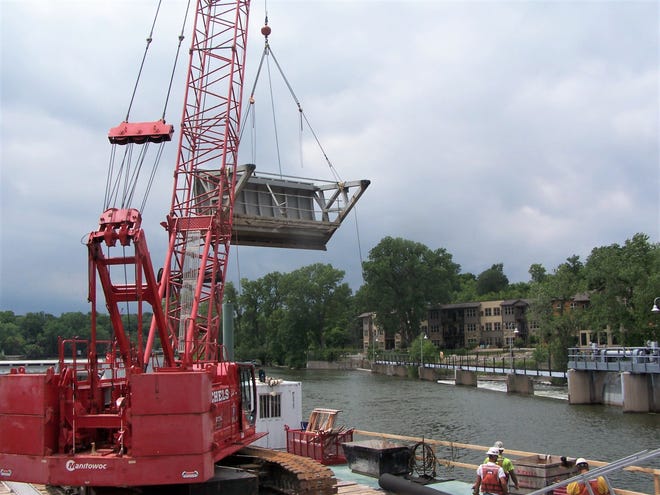 Contractors use a crane to lift a Tainter gate at the lower Fox River dam in Appleton.