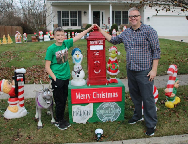 Michael Styer, right, and his son Cole are shown in front of their home at 928 Greenlea Drive in Marion. Known as "A Christmas House," the Styer home has become a holiday season destination for people who enjoy driving around and looking at Christmas lights. The house is lighted up at dusk daily now through New Year's Eve.