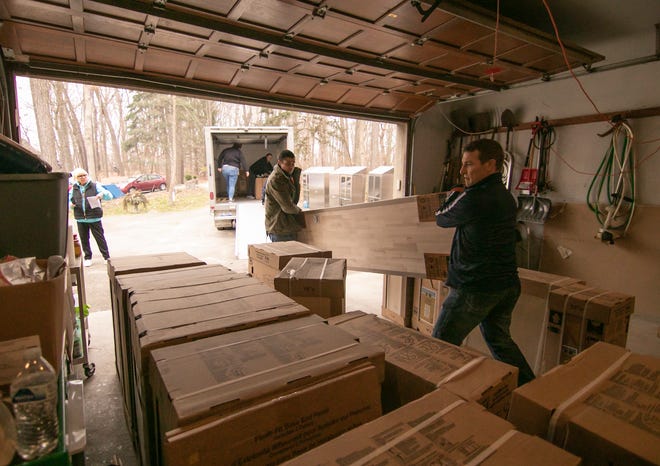 As April Tyler watches at left, Home Depot volunteers Derek Shortt, center, and Jeromy Helm unload cabinets to store pet supplies for the Chuck Waggin Pet Food Pantry Friday, Dec. 9, 2022.