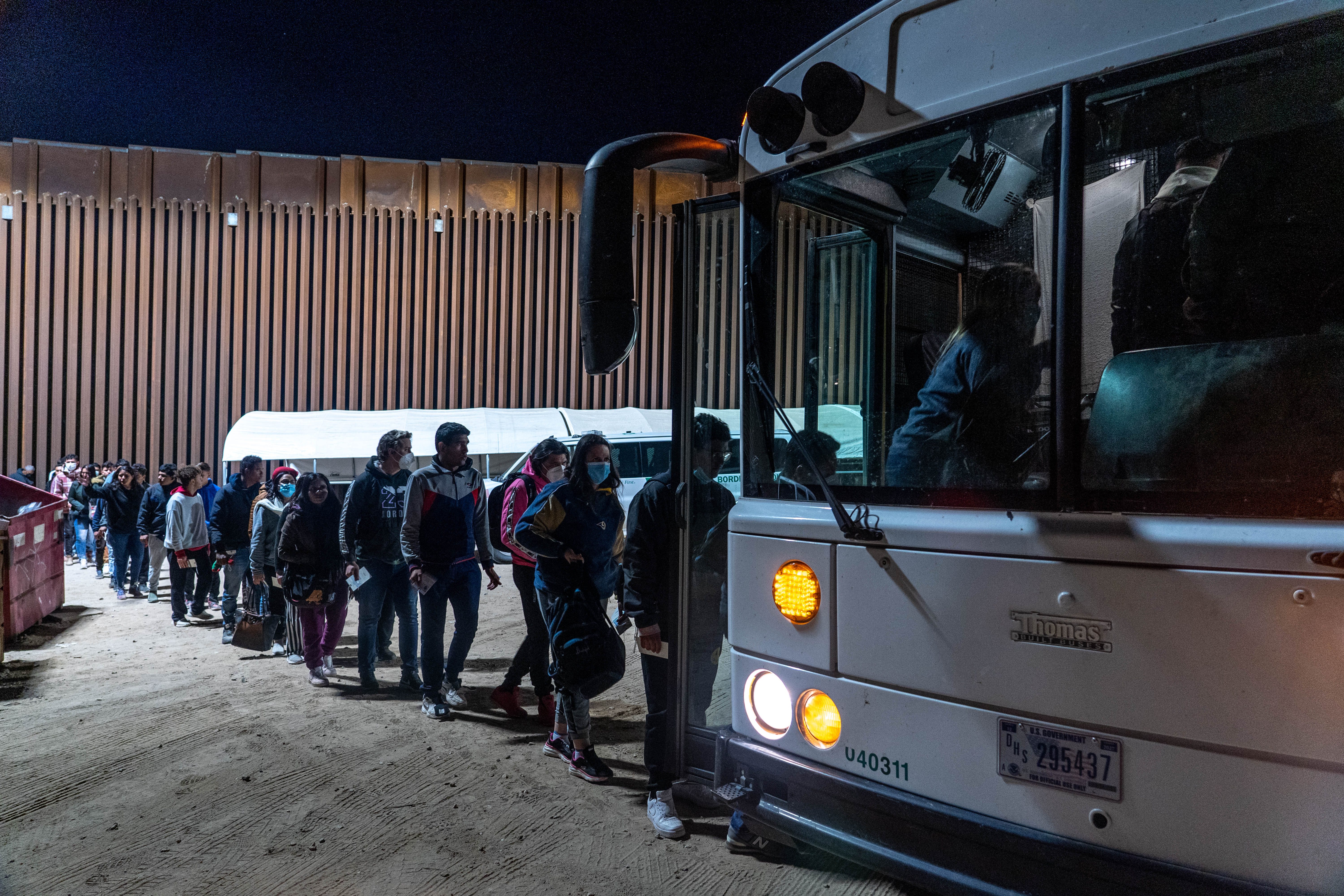 Migrants and asylum seekers board a transport bus after being detained by U.S. Border Patrol agents in Yuma County, near the Cocopah Indian Tribe's reservation on Dec. 8, 2022. Border Patrol agents estimated the group to be about 700 people.