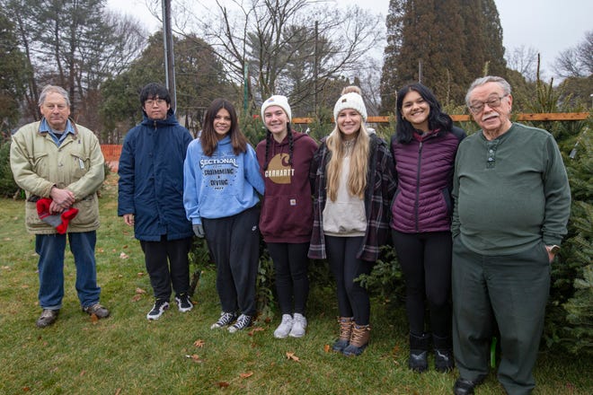 From left Christian Darby, Seungil Hwang, Ella Schult, Nicole Riemer, Celina Roy, Isabella Rodriquez, and Loren Salzman pose for a photo on Saturday, Dec. 10, 2022, during the YMCA Retired Men's Club Christmas tree sale at Highcrest Centre in Rockford.