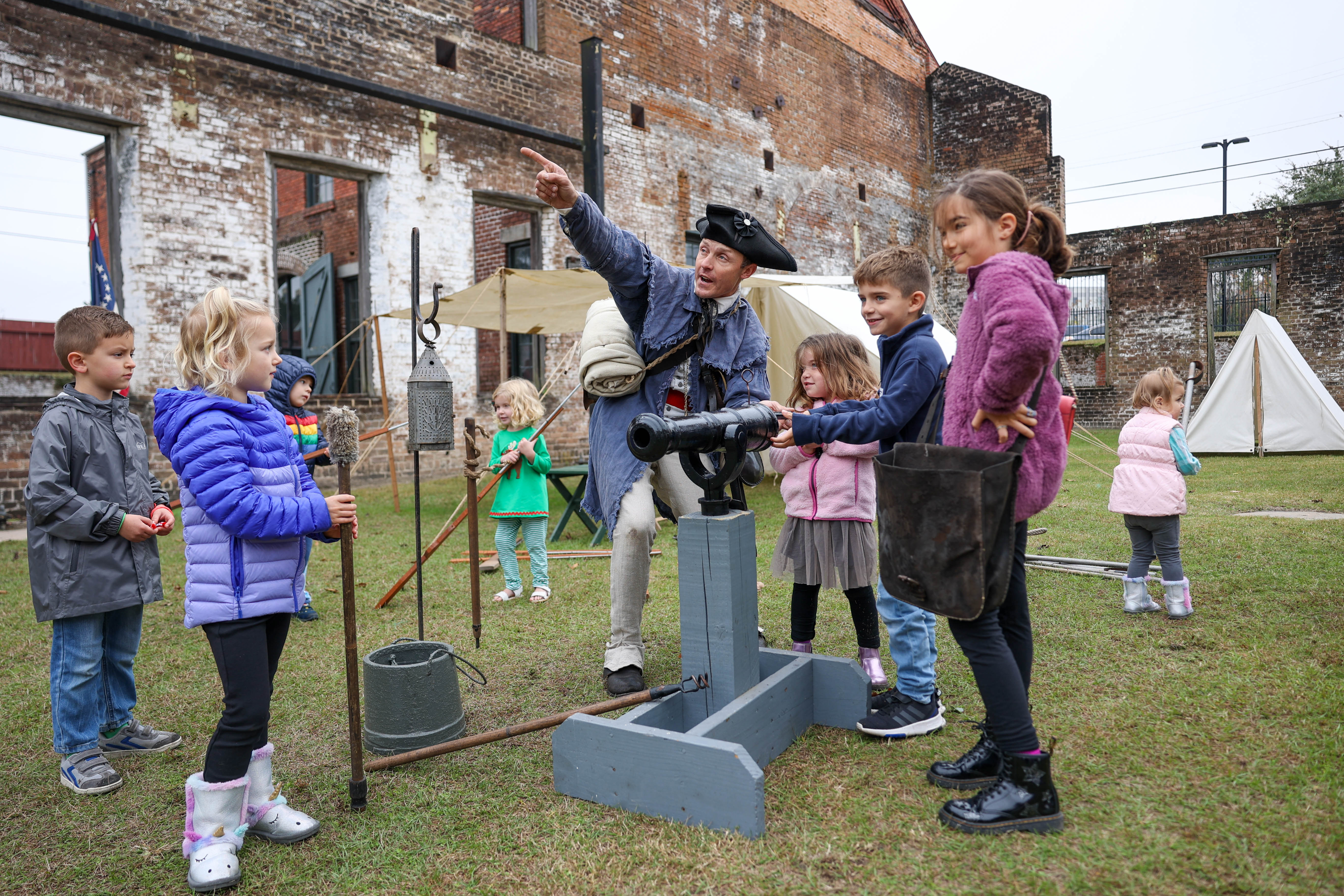 역사 통역사 아론 브래드포드(Aaron Bradford)가 10년 2022월 <>일 토요일 조지아 주립 철도 박물관에서 열린 사바나 산타 트레인 중 "양철 병사" 자원 봉사자 그룹에게 대포를 발사하는 방법을 보여줍니다.