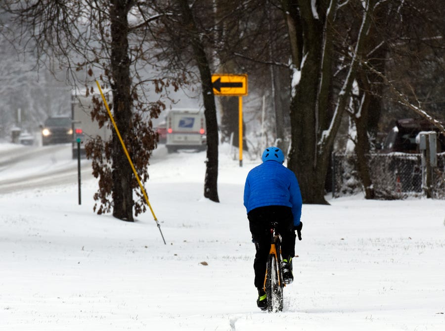 A cyclist makes his way through snow along Lakeshore Drive, Friday, Dec. 9, 2022, in St. Joseph, Mich., after a storm moved through Southwest Michigan. (Don Campbell/The Herald-Palladium via AP) ORG XMIT: MIBEN555