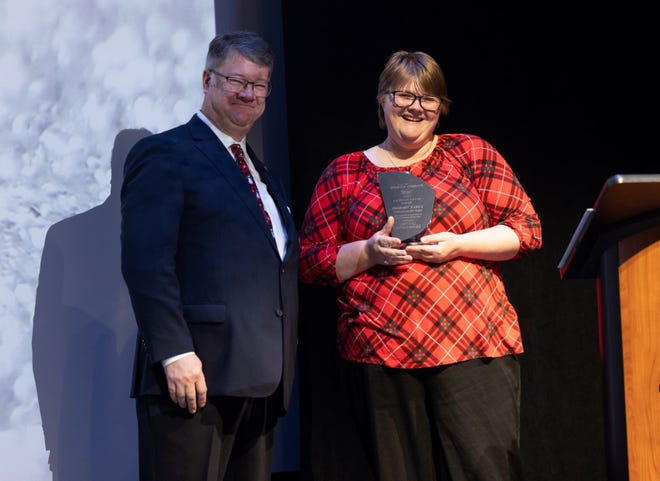 The 2022 Service Excellence Award Winner, Carol Vroman (right), and Reg Smith (left) stand on stage on Wednesday, Dec. 7 at the Great Lakes Center for the Arts during the Celebration of Champions award ceremony.
