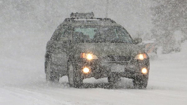 Cars slowly make their way as heavy snow falls on 