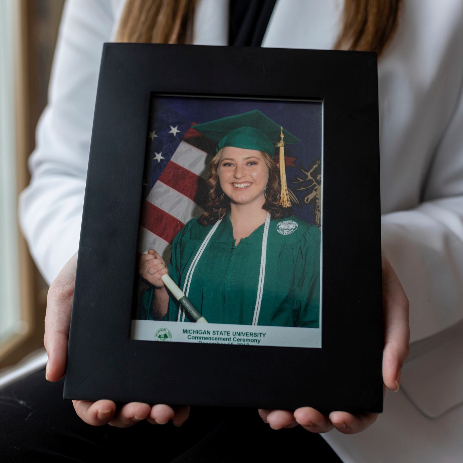 Hannah Smith, 25, holds a portrait of her during the Michigan State University commencement ceremony inside her home in Genesee County, Michigan, on Thursday, Dec. 8, 2022. Smith filed a complaint with the Office for Civil Rights alleging Michigan State mishandled her sexual harassment case.  (Via OlyDrop)