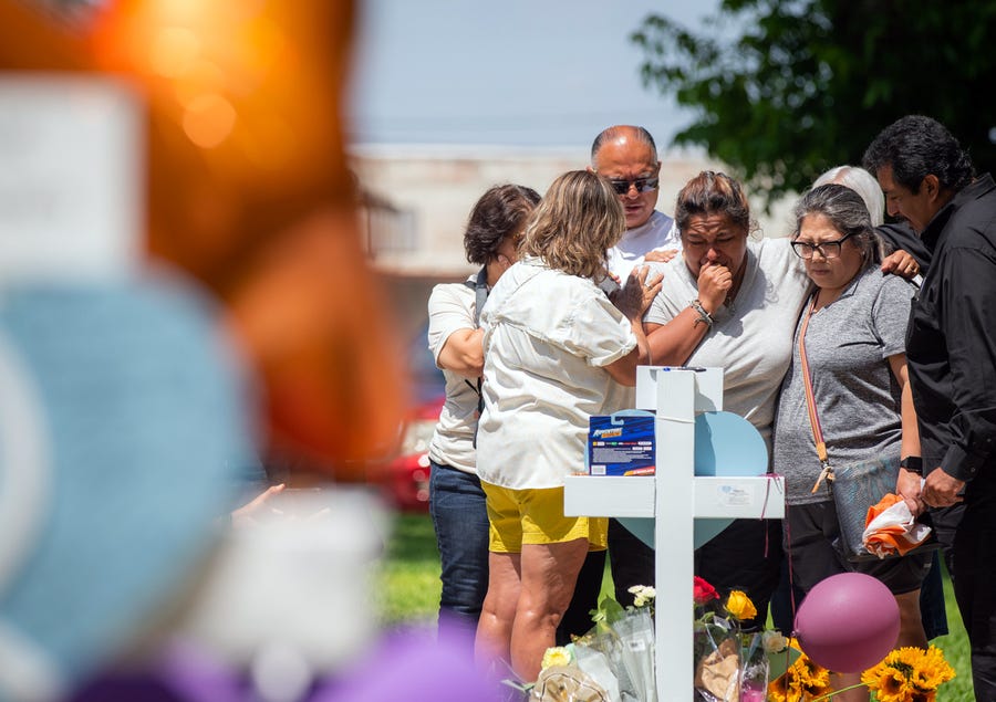 May 27, 2022: Mourners place flowers, candles and tokens on crosses for each of the Robb Elementary School shooting victims at a memorial put up in the Uvalde Town Square.