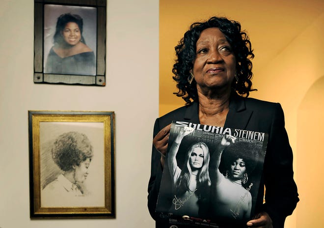 Dorothy Pitman Hughes poses in her St. Johns, Florida, home on Sept.  24, 2013, with a poster using a 1970's image of herself and Gloria Steinem. Hughes, a pioneering Black feminist, child welfare advocate, and activist died on  Dec. 1, 2022, in Tampa, Florida. She was 84.
