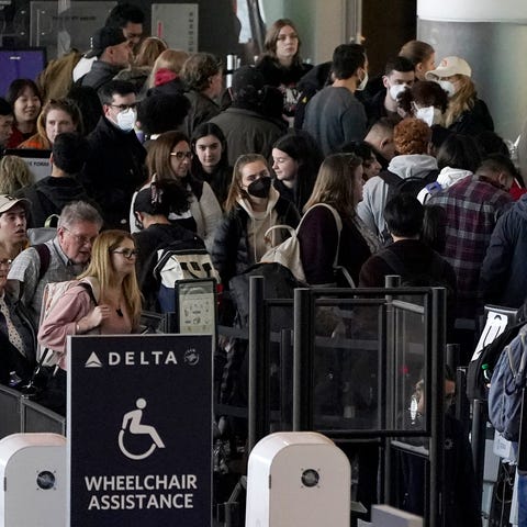 Travelers stand in line at a security checkpoint b