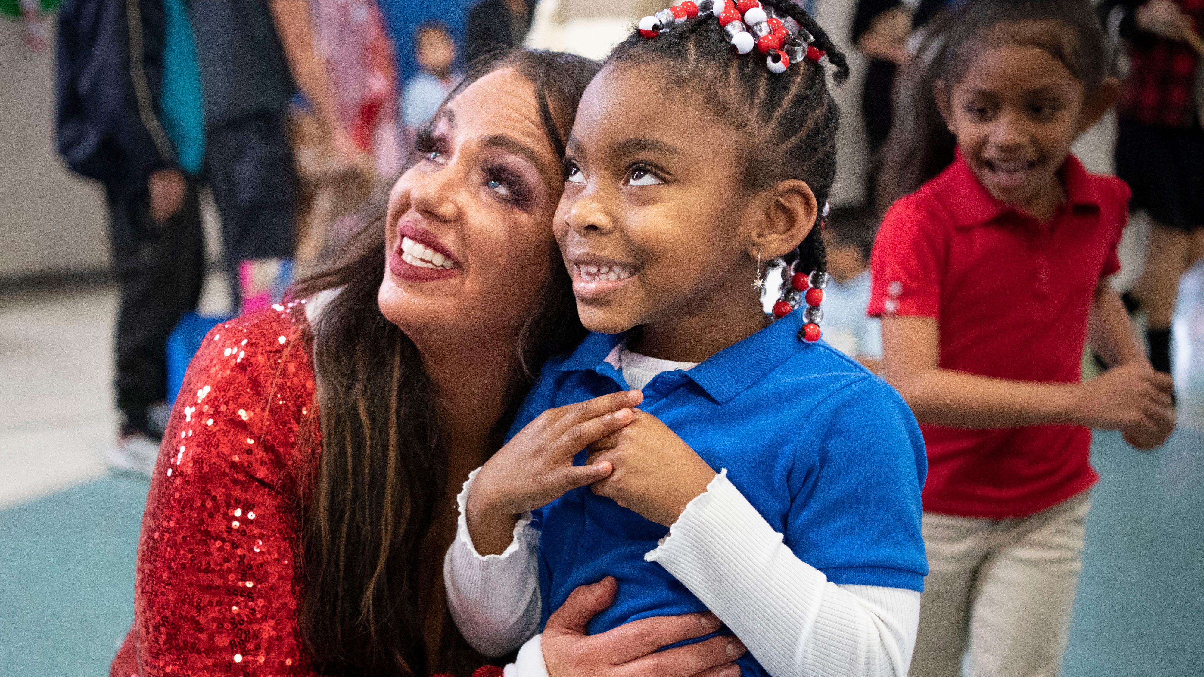 Tusculum Elementary School first grade teacher Laura Timbario-Quering hugs first grader Katrina Holman during a holiday celebration Wednesday, Dec. 14, 2022 in Nashville, Tenn. Timbario-Quering organized a Secret Santa giveaway for 150 elementary school students.