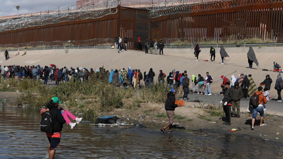 December 13, 2022: Migrants walk across the Rio Grande to surrender to US Border Patrol agents in El Paso, Texas, as seen from Ciudad Juarez, Chihuahua state, Mexico.