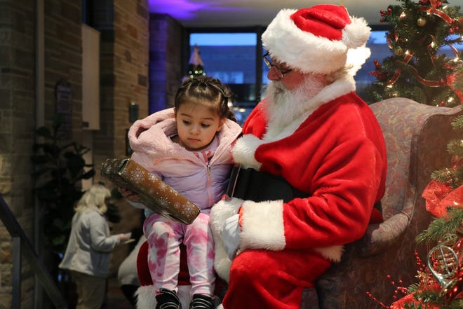 Santa Claus presents a gift to 3-year-old Amara Martin during the annual Sturgis Elks and Kiwanis Boots and Shoes event on Tuesday, Dec. 13, 2022.