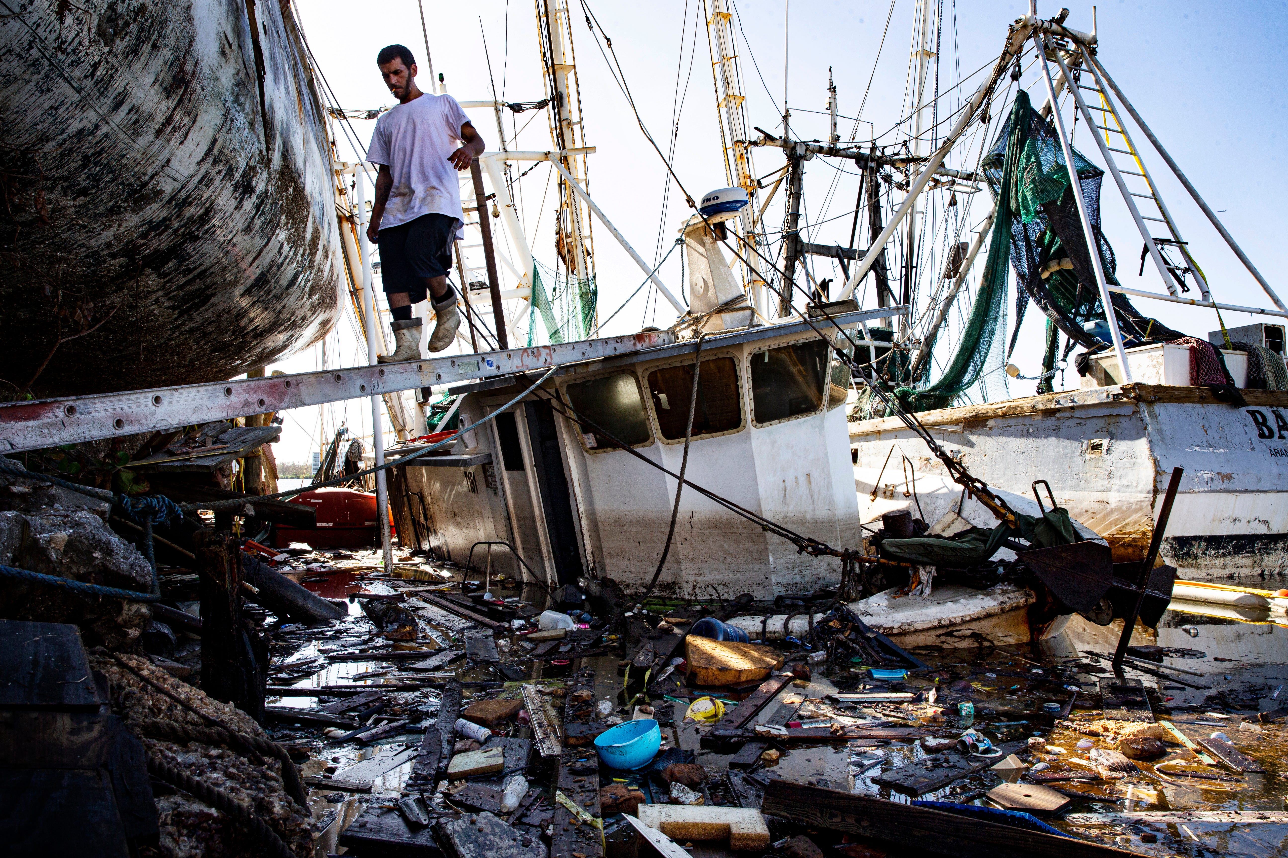 Kyle Lamb, the captain of the shrimp boat Babe, walks a plank to cross over the sunken shrimp boat Perseverance. The Perseverance sank in Hurricane Ian at the shrimp docks on Fort Myers Beach. The Babe was one of the boats that survived the storm and left several days later on a fishing trip.  