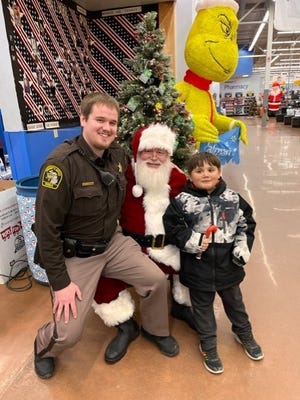 Deputy Joshua Vroon of the Ionia County Sheriff's Office, Santa Claus and Boyce Elementary School's Evan Solis pose for a photo at the annual "Shop with a Cop" event Dec. 14 at Walmart.