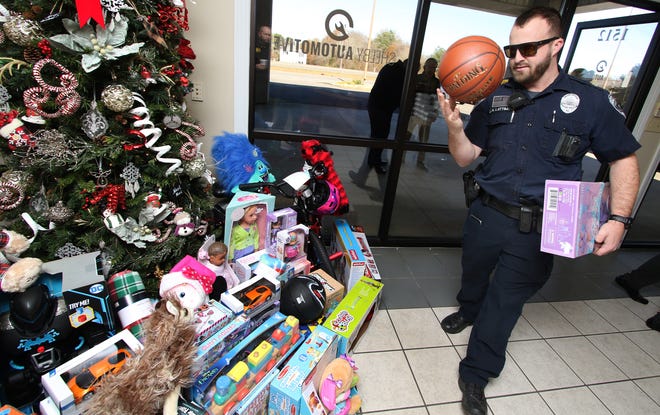 Shelby Police Officer J.H. Lattimore adds donated toys to the growing collection during a toy run held Friday afternoon, Dec. 16, 2022, at Shelby Automotive.