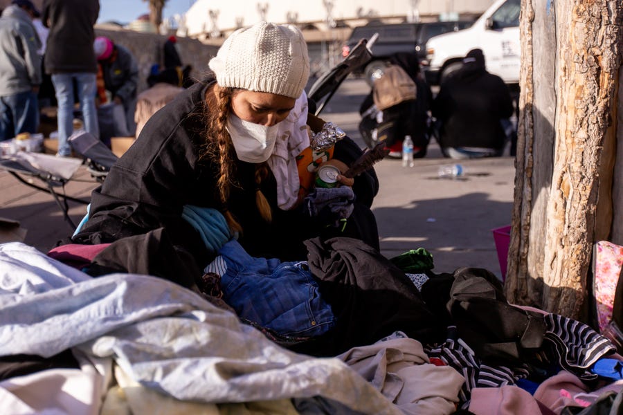 A migrant looks through clothes that were donated to stay warm on the streets of El Paso, Texas, on Saturday, Dec. 17, 2022, after being released after crossing into the U.S.