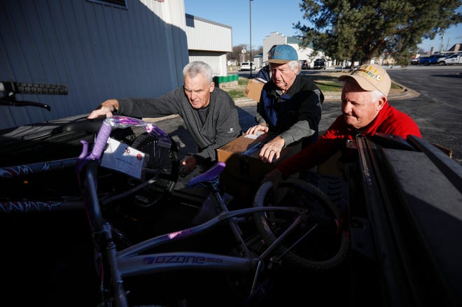 Volunteers Mark Nelson (left), Lanny Brent (center), and Brad Hoppes load bikes and gifts into the back of a truck at the Crosslines warehouse during Share Your Christmas distribution on Friday, Dec. 16, 2022.