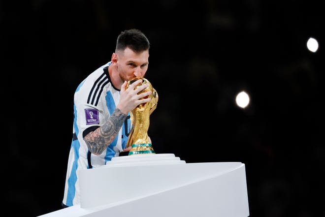 De Argentijnse spits Lionel Messi kust de WK-trofee na het winnen van de WK-finale van 2022 tegen Frankrijk in het Lusail-stadion. 
