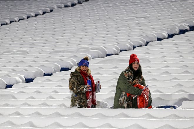 Buffalo Bills fans clear the snow off their seats during warmups before an NFL football game between the Buffalo Bills and the Miami Dolphins in Orchard Park, N.Y., Saturday, Dec. 17, 2022. (AP Photo/Joshua Bessex) ORG XMIT: NYGP