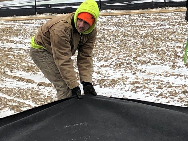 Aiden Yacklin, a senior at Alliance High School, helps stretch out cloth for SCG Fields, which is renovating the Aviators' baseball and softball fields. SCG Fields hired six students in the school's construction trades program as paid part-time interns.