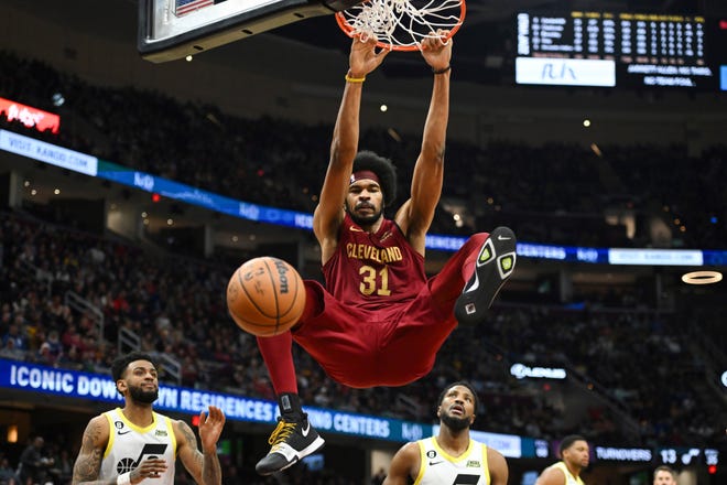 Cleveland Cavaliers center Jarrett Allen hangs from the rim after dunking during the second half of an NBA basketball game against the Utah Jazz, Monday, Dec. 19, 2022, in Cleveland. (AP Photo/Nick Cammett)
