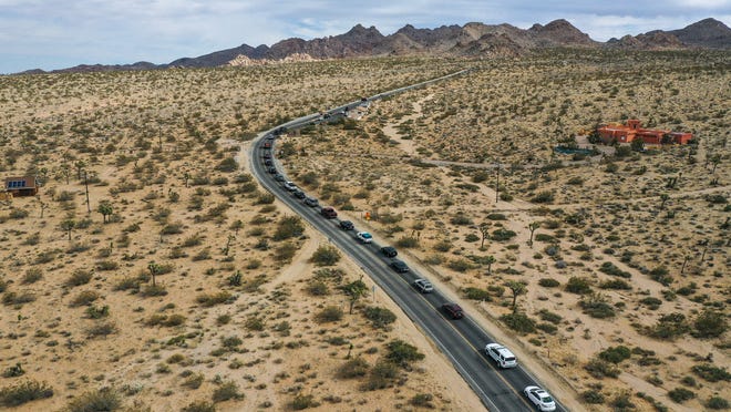 A long line of cars waits to get in to Joshua Tree National Park, Calif., on a Friday afternoon, January 28, 2022.  The park has seen more visitors as its popularity increases.