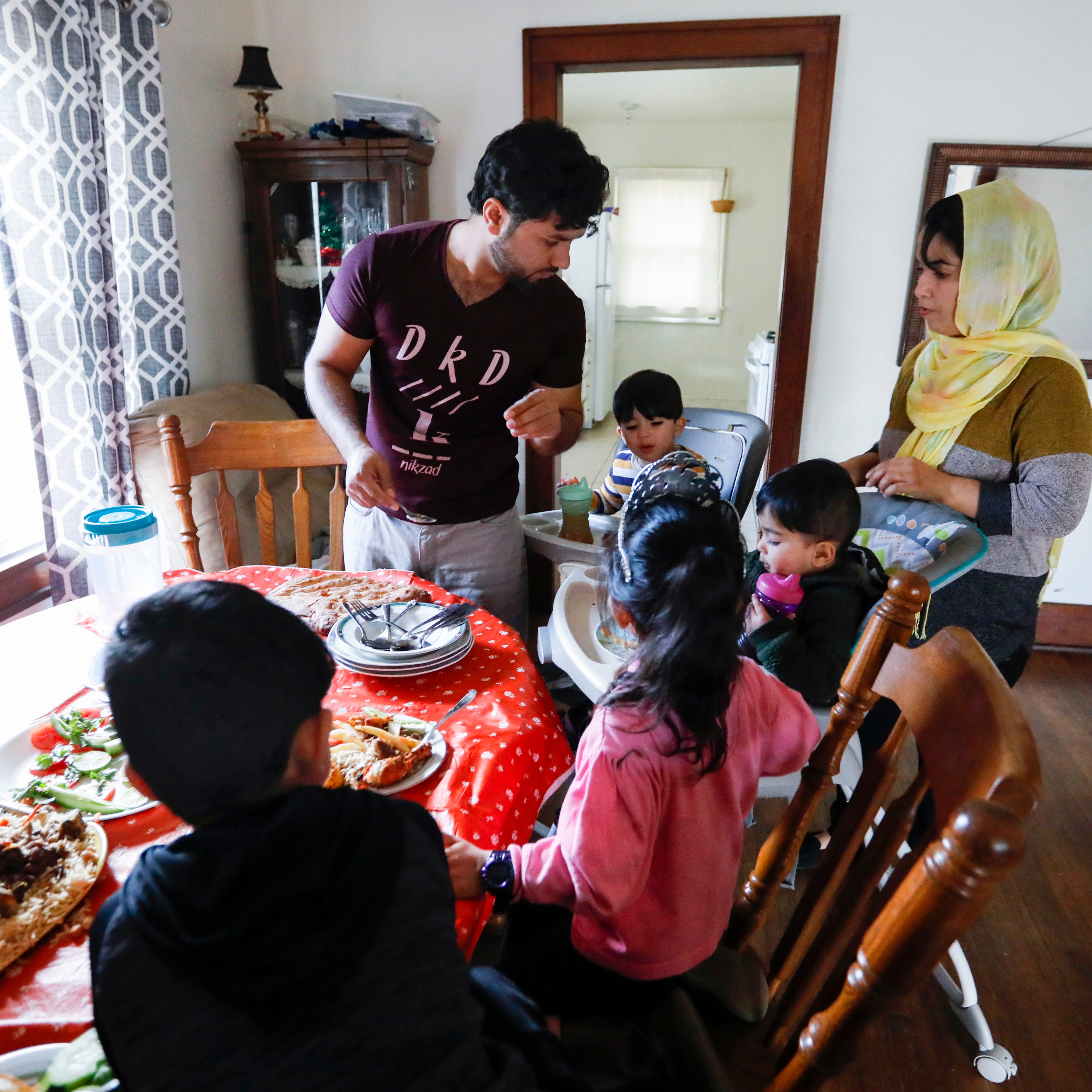 The Noori family, Romal (center), Farishta (right), 2-year-old Mohammad Sodais (back center), 18-month-old Mohammad Sorosh (middle), 6-year-old Behishta (front right), and 6-year-old Abdul Bais (front) sit down for lunch at their home on Saturday, Dec. 17, 2022. Romal Noori worked as a translator for the U.S. military for almost a decade and fled Afghanistan with his family last fall as U.S. troops withdrew and the Taliban took over.