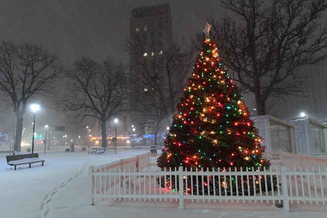 A man walks his dog near an illuminated Christmas tree during heavy snowfall on December 16, 2020 in Wilkes Barre, Pennsylvania.