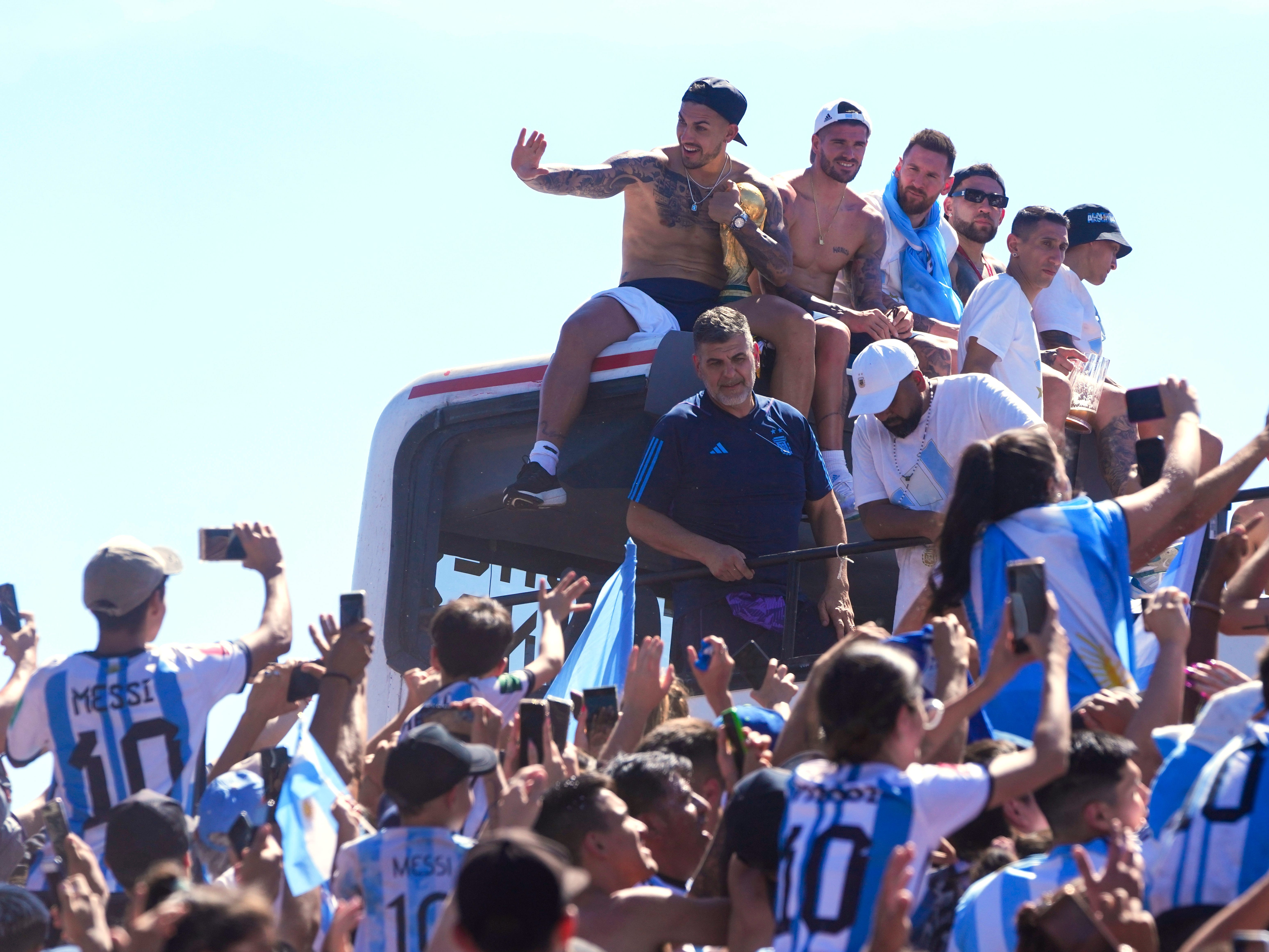 Argentina soccer players (from left) Leandro Paredes, Rodrigo De Paul, Lionel Messi and Nicolas Otamendi sit on the top of a bus during their team's homecoming parade after winning the World Cup.