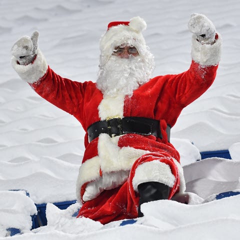 A fan dressed as Santa sits ready for a game betwe