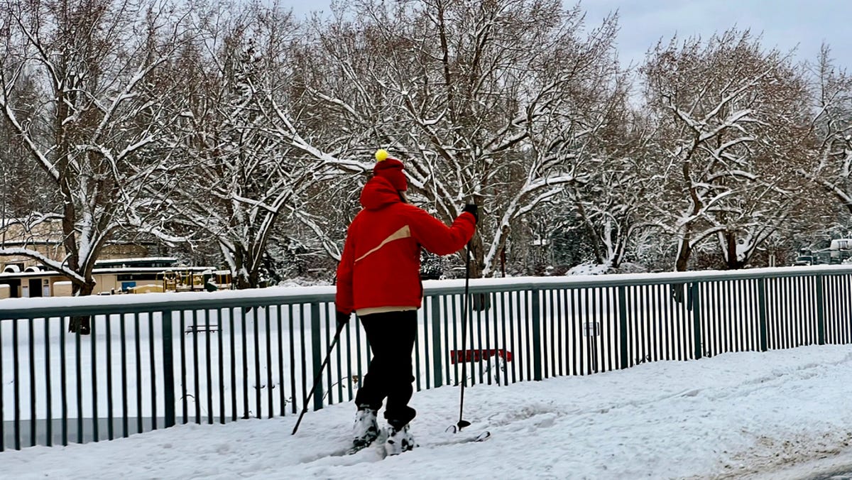 A person cross-country skis on a sidewalk in Bellingham, Wash., early Tuesday, Dec. 20, 2022. Heavy snow, freezing rain and sleet have disrupted flights and motorists trying to travel across the Pacific Northwest.