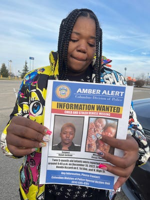 Dec 21, 2022; Dayton, Ohio, USA; Wilhelmina Barnett, mother of twins Kason and Kyair Thomas, holds up an information wanted sign in a Walmart parking lot in Dayton.