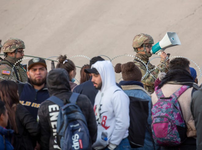 Migranten steken de Rio Grande over en benaderen de Texas National Guard om te vragen wanneer Customs and Border Protection hen asiel zal verlenen, 20 december 2022, in El Paso, Texas.
