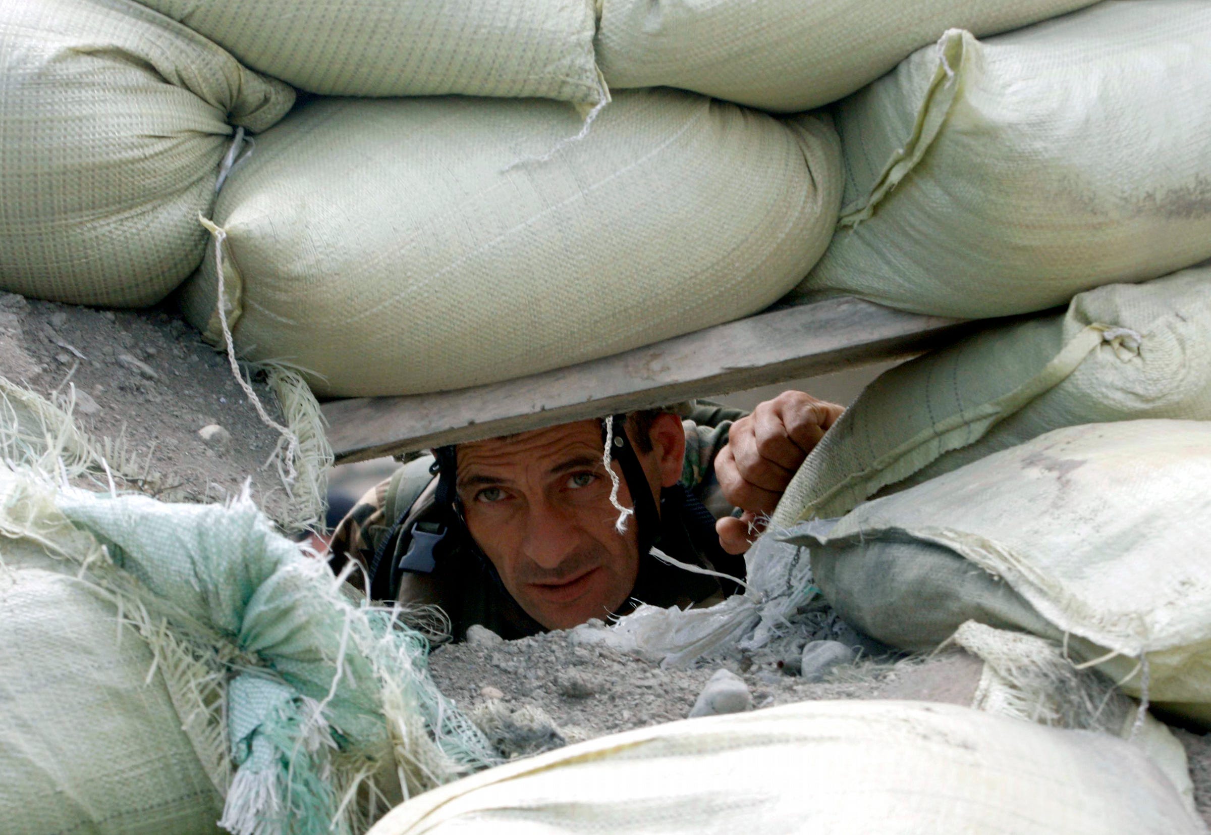 A Georgian soldier watches through a gun-port of his fortified foxhole looking toward of South Ossetian separatist government forces' positions in the ethnic Georgian village of Ergneti, on Tuesday, Aug. 5, 2008. Six people died in fighting that broke out late Friday and early Saturday, including sniper and mortar fire between South Ossetian and Georgian forces. The breakaway republic of South Ossetia split from Georgia in the early 1990s after brief but violent conflict.       (AP Photo/George Abdaladze) ORG XMIT: MOSB138