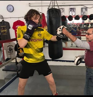 Harold Wilen of the Sarasota Boxing Club holds the hand pads for 16-year-old Tarik Pehlic at the boxing gym of Tony Spain of Absolute Boxing with Tony Spain.