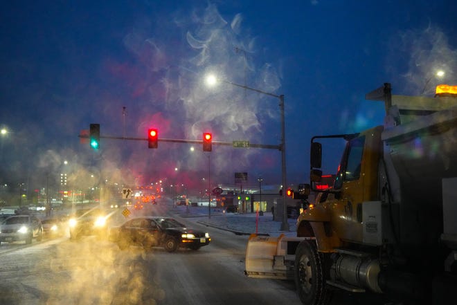 A snowplow stops a red light at the intersection of Fourth Street and Grand Avenue in West Des Moines on Wednesday.