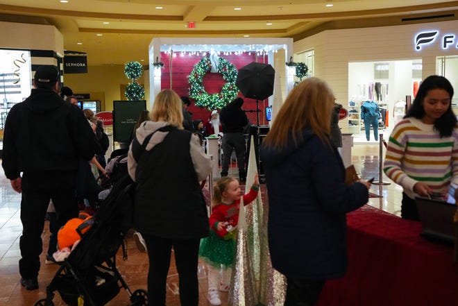 Last-minute holiday shoppers stand in line for a photo with Santa at Jordan Creek Town Center in West Des Moines on Wednesday.