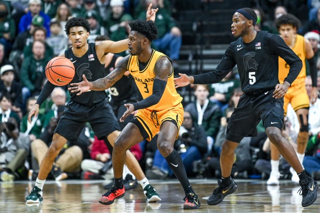 Oakland's Rocket Watts, center, passes the ball as Michigan State's Jaden Akins, left, and Tre Holloman defend during the first half on Wednesday, Dec. 21, 2022, at the Breslin Center in East Lansing.