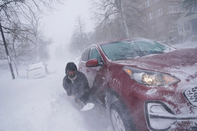 Gamaliel Vega tries to dig out his car on Lafayette Avenue after he got stuck in a snowdrift about a block from home while trying to help rescue his cousin, who had lost power and heat with a baby at home across town during a blizzard in Buffalo, N.Y., on Saturday, Dec. 24, 2022.