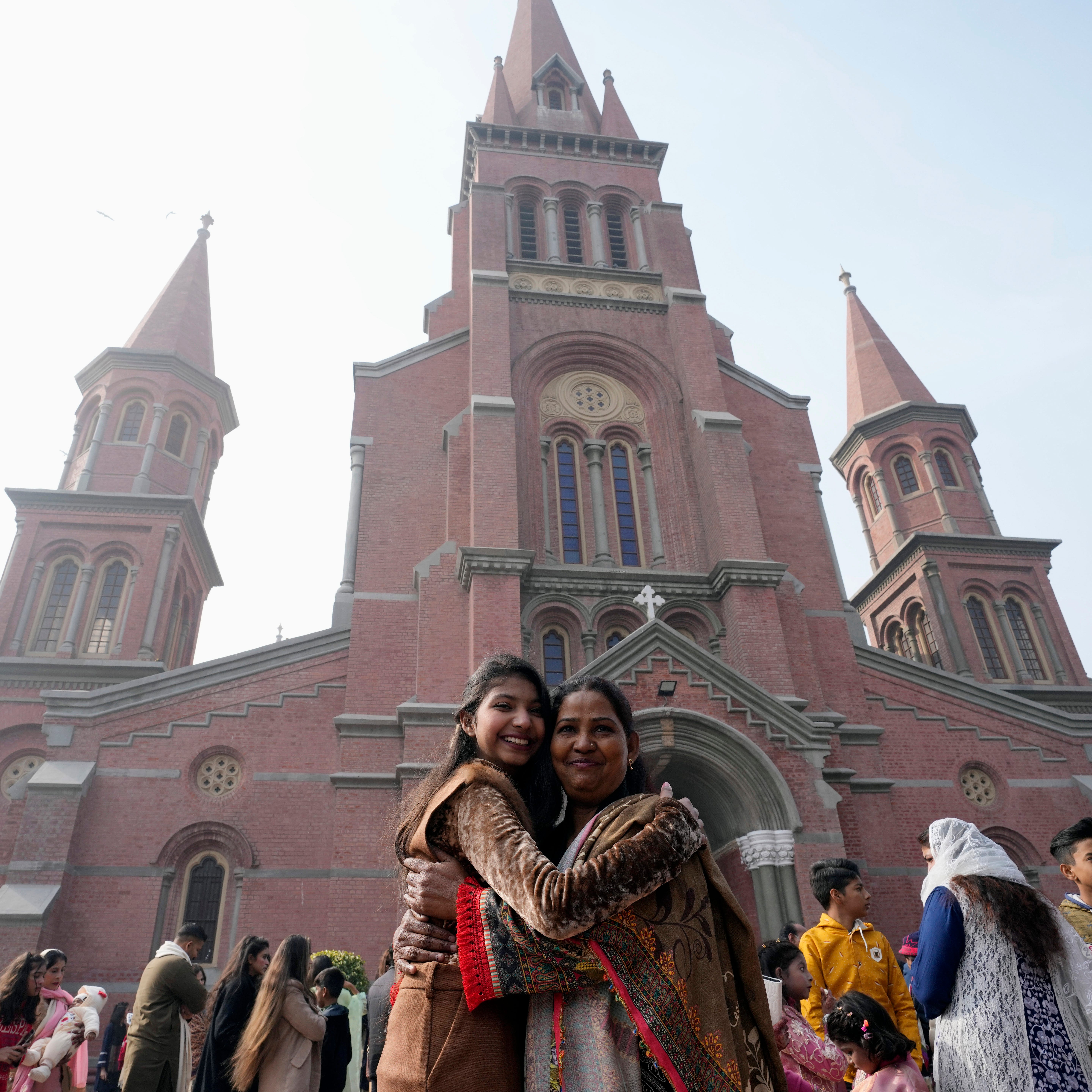 Two Christian women embrace outside Sacred Heart Cathedral before Christmas Mass in Lahore, Pakistan, on Dec. 25, 2022.